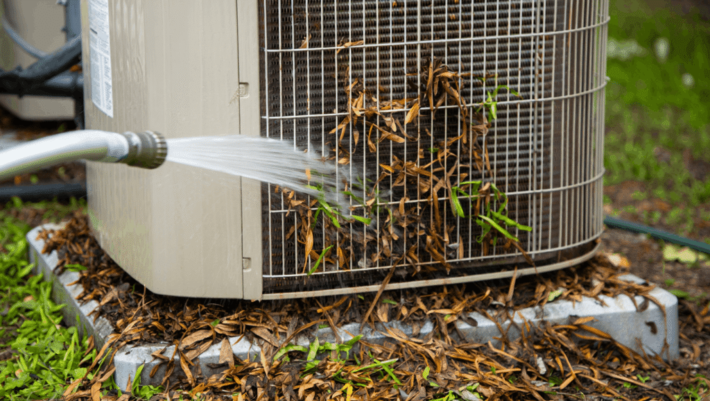 Cleaning a dirty outdoor AC condenser unit with a garden hose