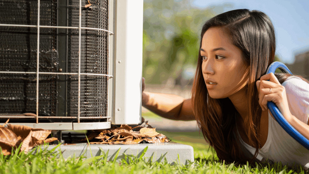 Homeowner inspecting a central AC condenser unit that is not cooling the house
